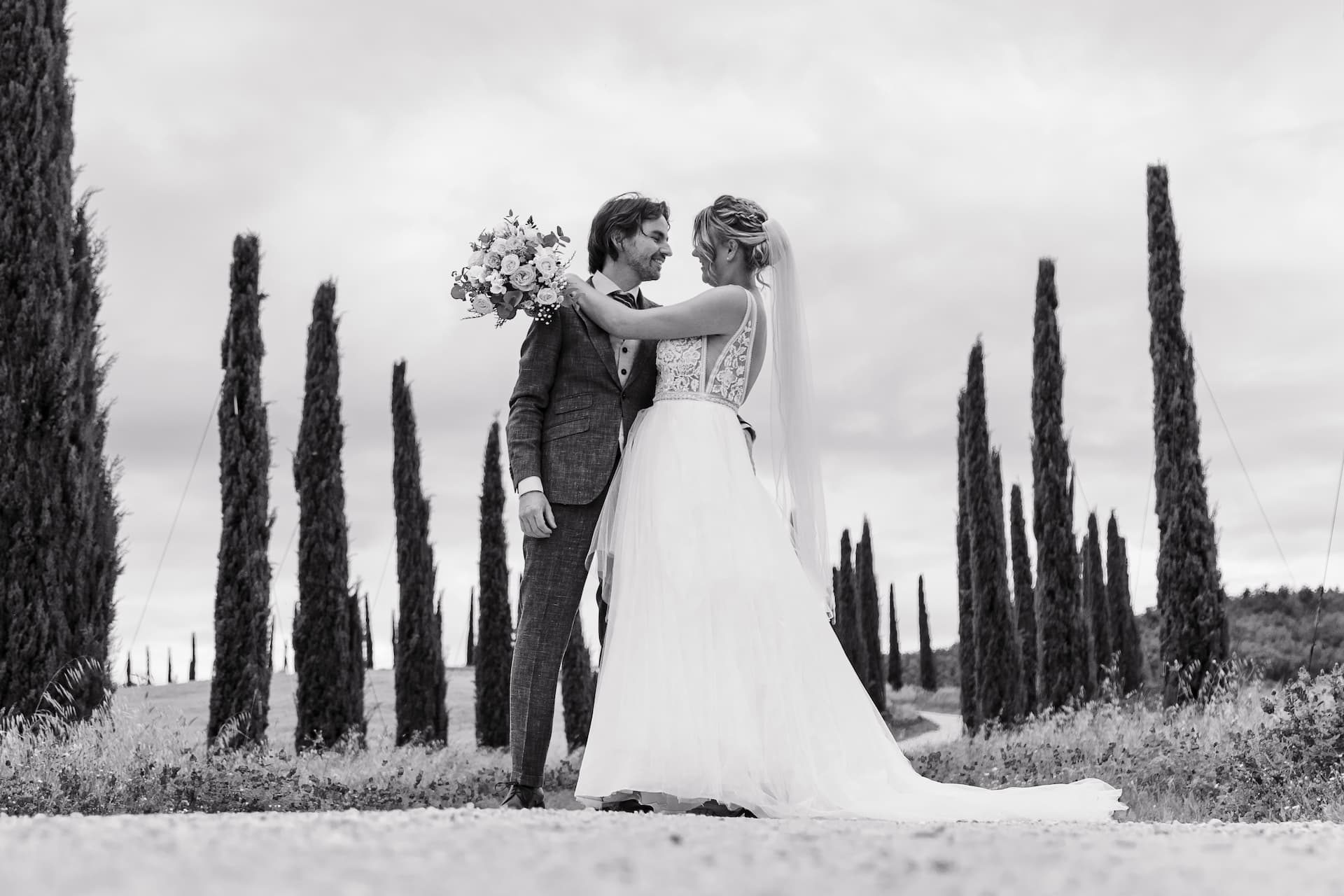 Bride and groom among the cypress trees, black and white